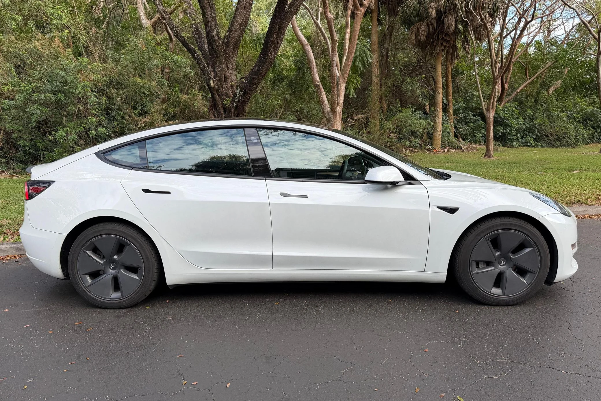 Original side-profile photo of an electric sedan before a wheel swap preview