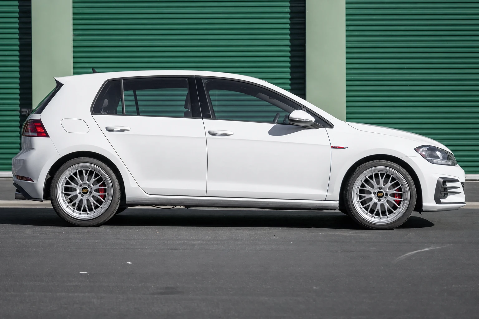 AI wheel swap showing bright silver wheels on a dark hatchback