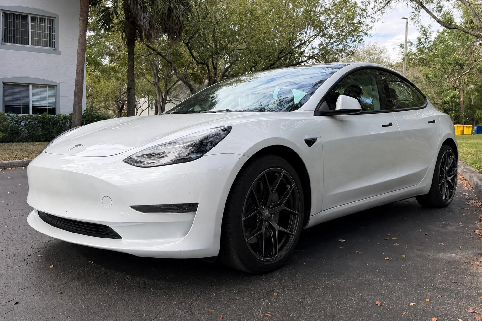 AI wheel swap preview with satin black wheels on a light electric sedan